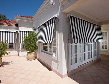 Kenlow awnings in black and white stripes on a house exterior