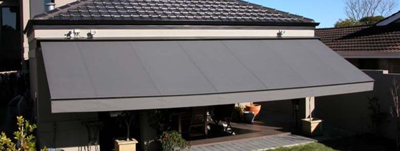 Grey folding arm awnings on house from kenlow