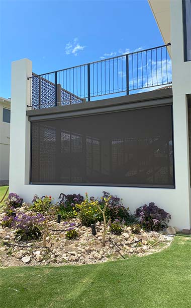 Green, blue house exterior with black outdoor blinds