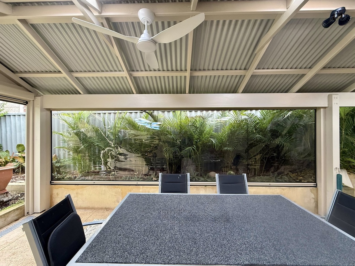 Clear outdoor blinds enclosing a patio with dining table in Perth