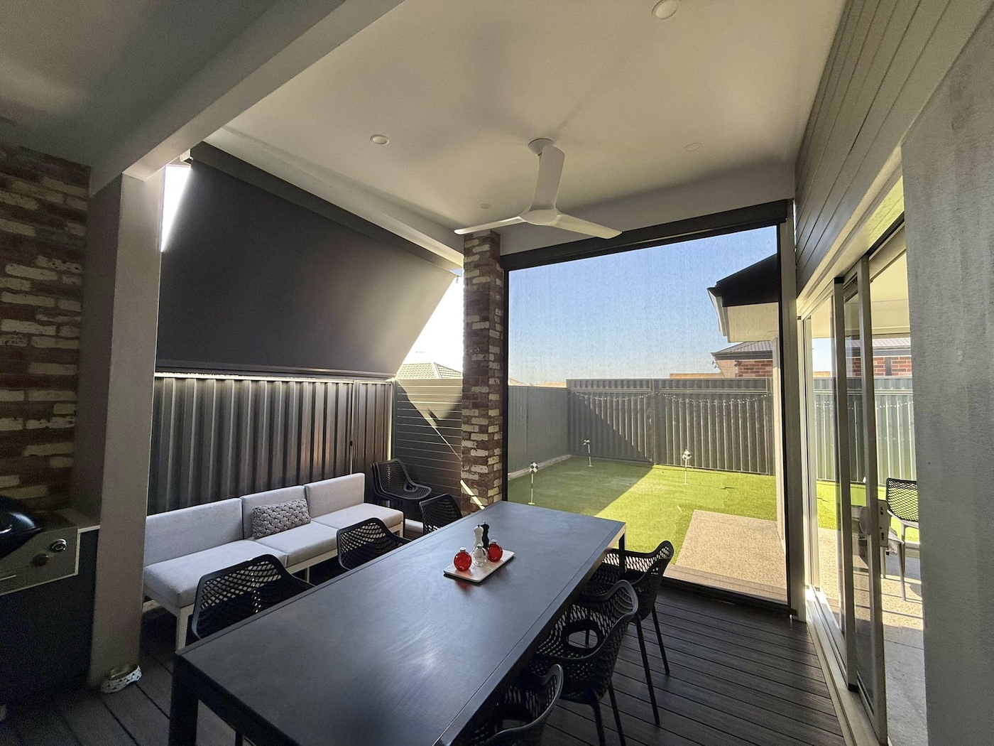 Alfresco dining area with a privacy blind lowered, overlooking the backyard
