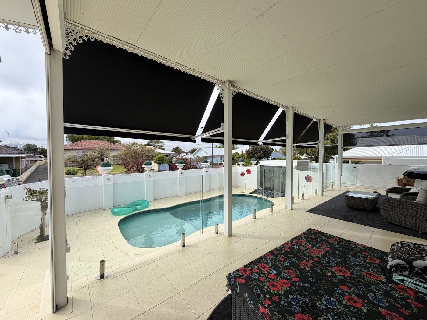 Black retractable awnings with decorative trim shading a patio beside a pool