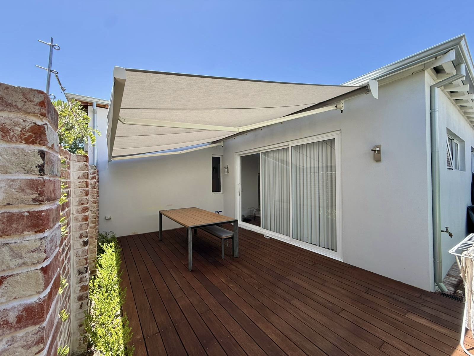 Folding arm awning shading a timber deck and outdoor dining table