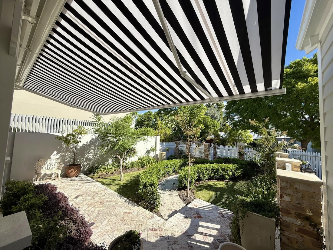 Black and white striped Perth awning shading a front verandah overlooking a landscaped garden