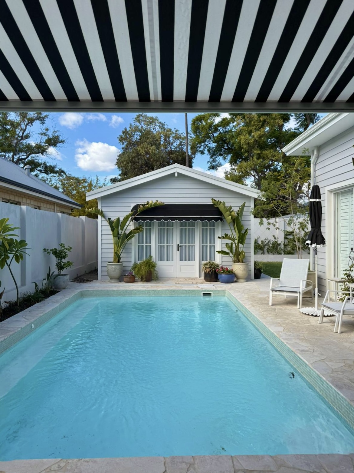 Black and white striped Perth awning shading a backyard pool and granny flat